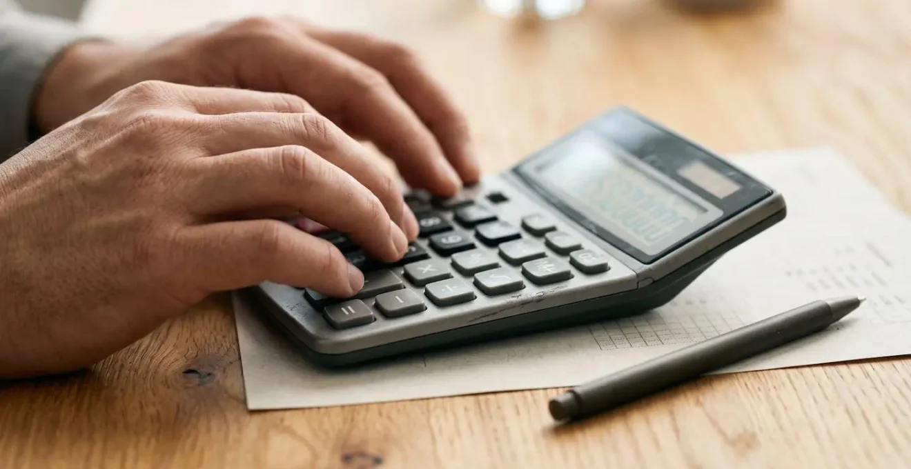 Vue rapprochée de mains professionnelles analysant des documents financiers avec calculatrice sur un bureau épuré
